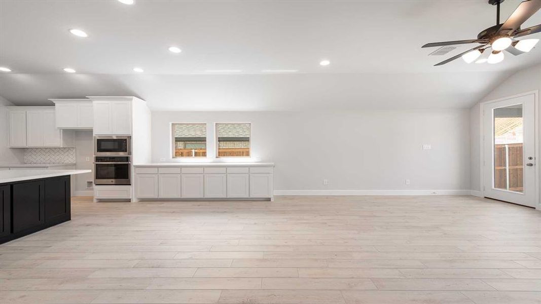 Kitchen featuring appliances with stainless steel finishes, white cabinets, backsplash, lofted ceiling, and ceiling fan