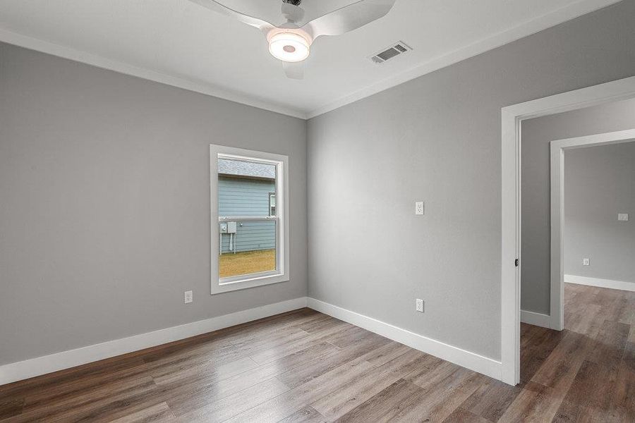 Unfurnished room with wood finished floors, a ceiling fan, and ornamental molding
