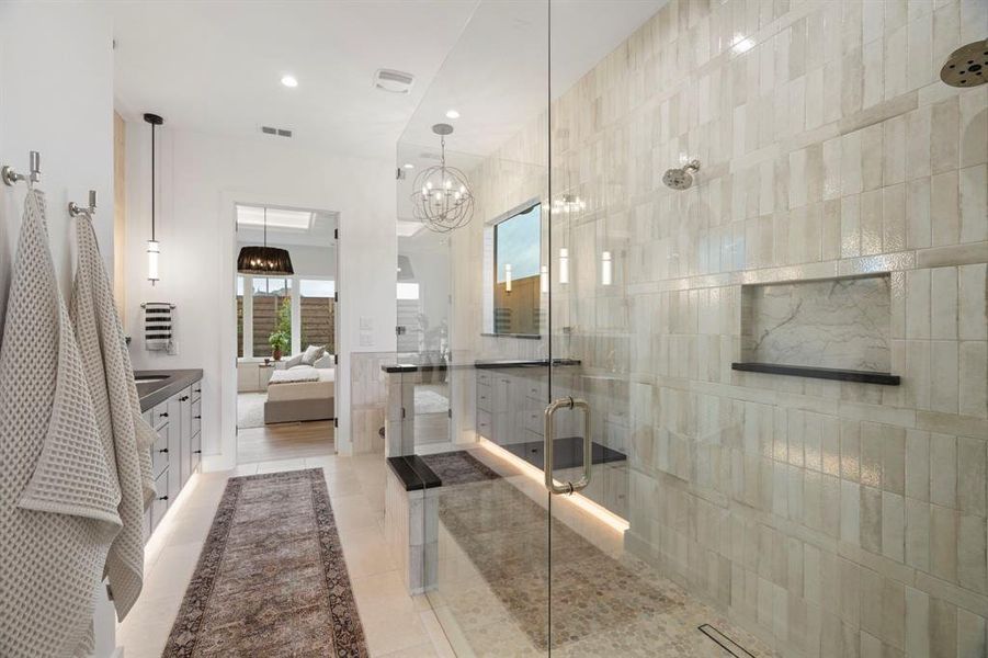 Bathroom featuring connected bathroom, a shower stall, two vanities, and suspended lighting Bathroom featuring connected bathroom, a shower stall, two vanities, and suspended lighting