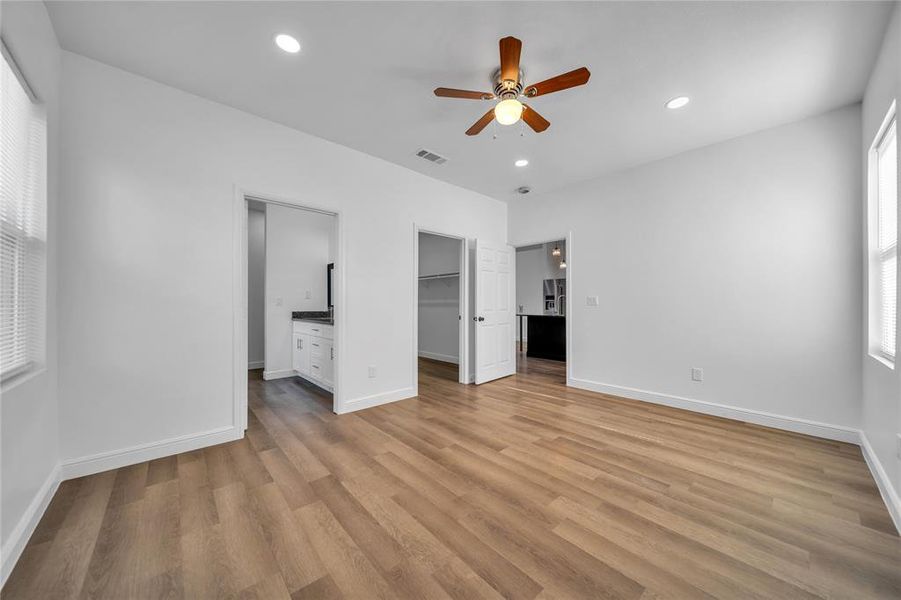 Unfurnished bedroom featuring a spacious closet, recessed lighting, light wood-style flooring, a ceiling fan, and connected bathroom