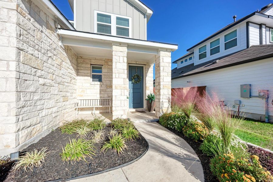 Entrance to property with stone siding, board and batten siding, and covered porch
