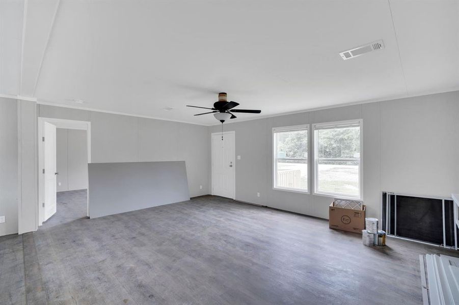 Spacious room featuring wood-finish flooring, light grey wall paneling, and white trim