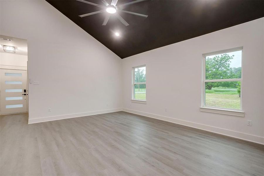 Unfurnished room featuring ceiling fan, wood finished floors, and high vaulted ceiling