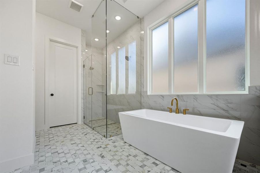 Bathroom with a freestanding bath, a marble finish shower, recessed lighting, and tile walls Bathroom with a freestanding bath, a marble finish shower, recessed lighting, and tile walls