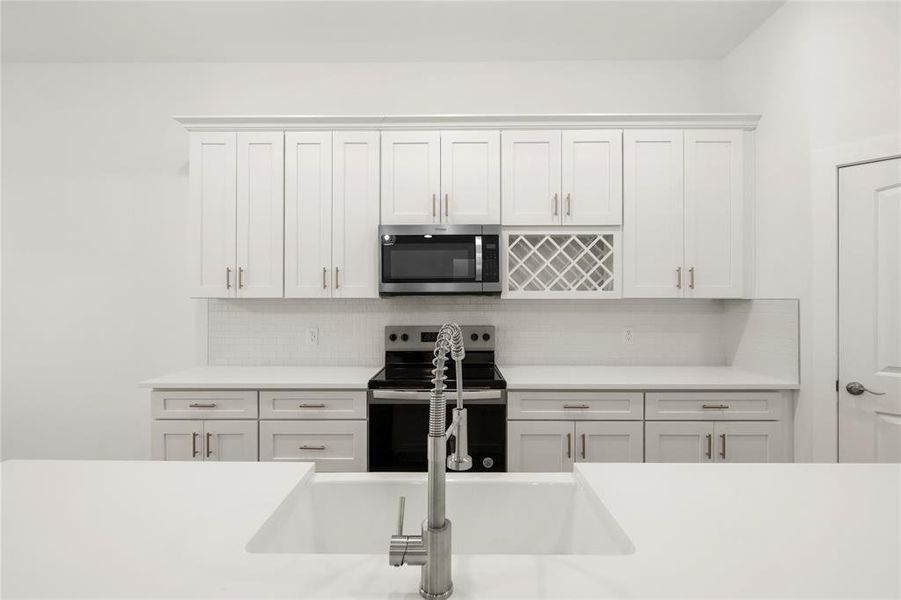 Kitchen with white cabinets, appliances with stainless steel finishes, tasteful backsplash, and sink