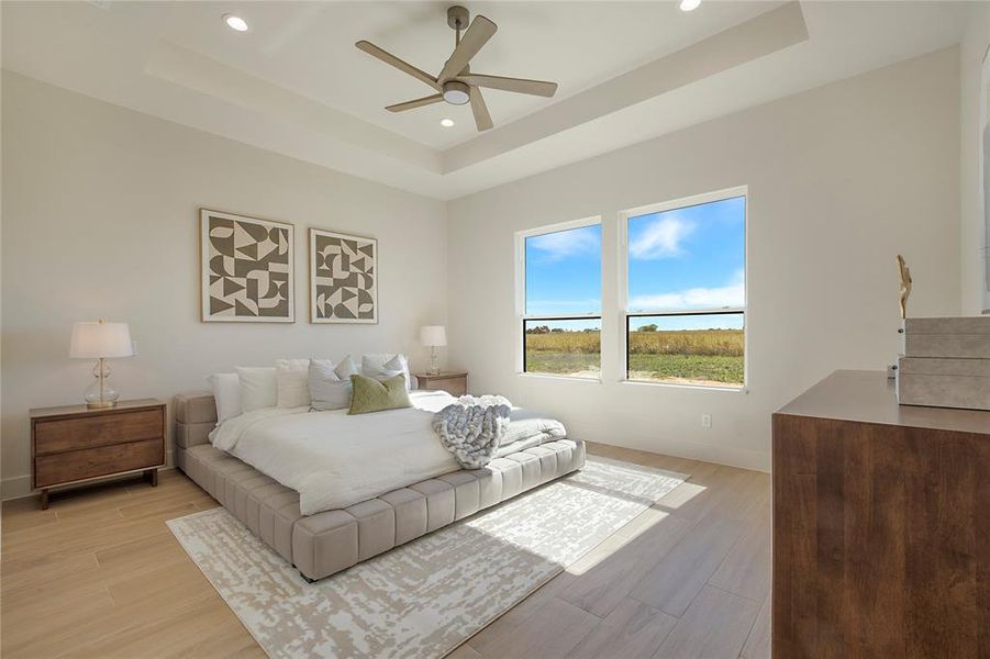 Bedroom with a tray ceiling, light wood-style flooring, recessed lighting, and a ceiling fan Bedroom with a tray ceiling, light wood-style flooring, recessed lighting, and a ceiling fan