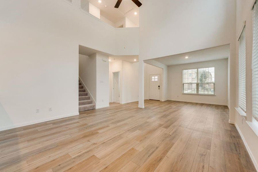 Unfurnished living room with high vaulted ceiling, light hardwood / wood-style flooring, and ceiling fan