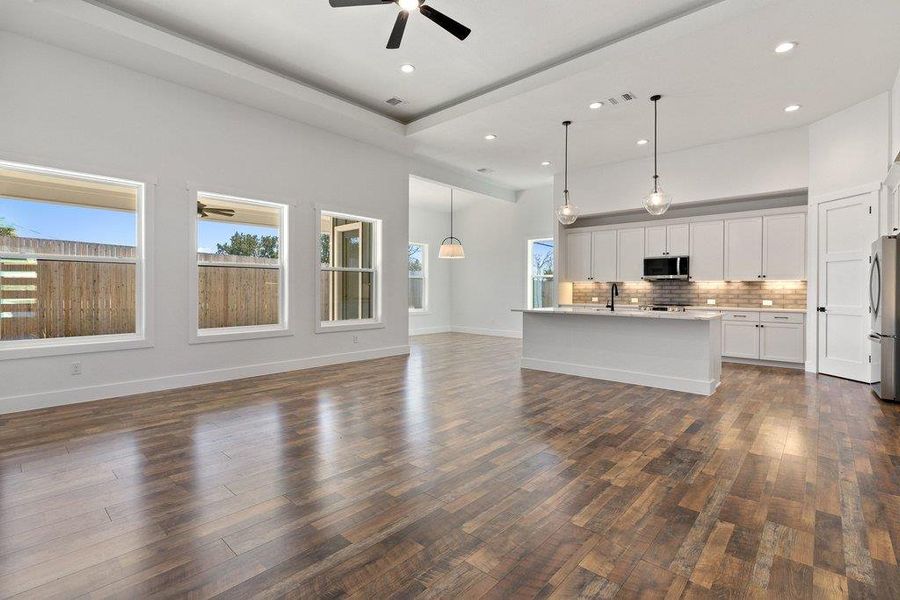 Unfurnished living room featuring a ceiling fan, dark wood-type flooring, recessed lighting, and a high ceiling