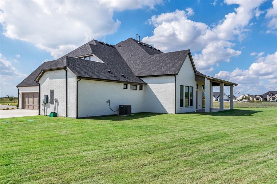 View of side of property featuring a garage, cooling unit, and a yard