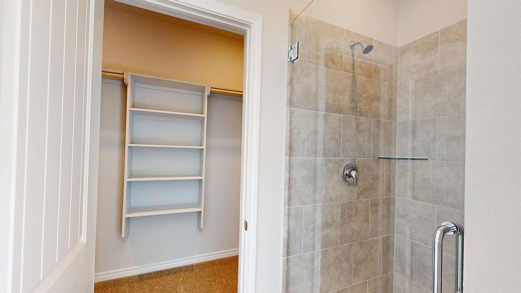 The bathroom features a tiled shower with a glass enclosure and a glass shelf