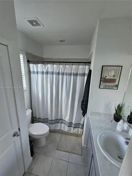 Bathroom featuring a single-sink vanity with a solid-surface countertop and a tile-surround shower combination