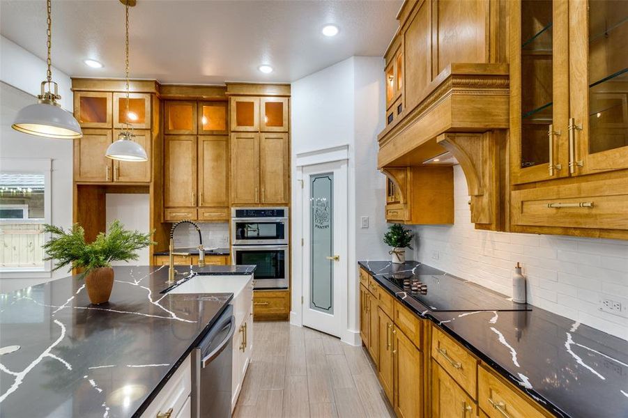 Kitchen with pendant lighting, sink, decorative backsplash, dark stone counters, and stainless steel appliances