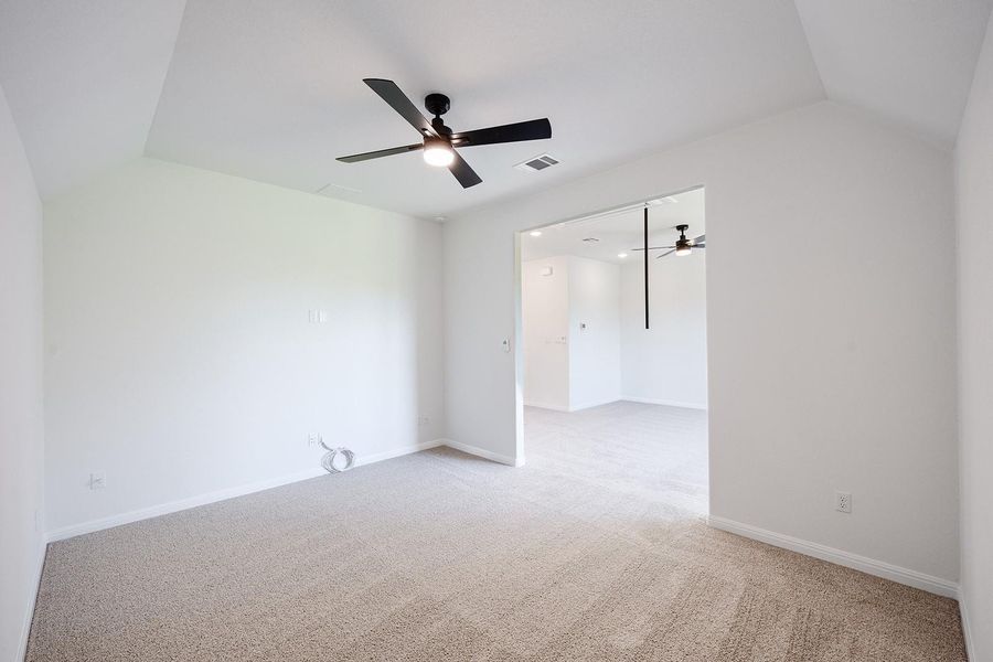 Empty room with ceiling fan, vaulted ceiling, light colored carpet, and baseboards Empty room with ceiling fan, vaulted ceiling, light colored carpet, and baseboards