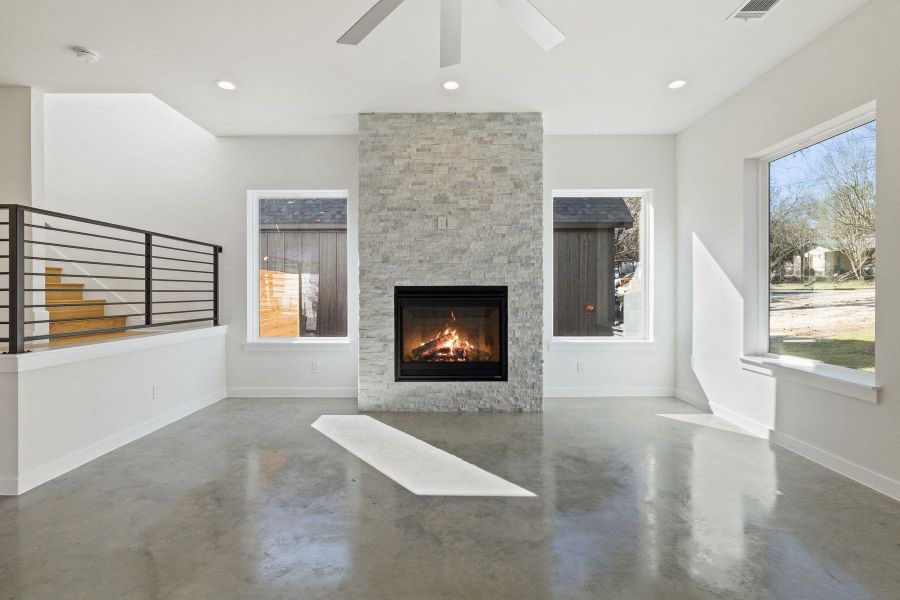 Living room with finished concrete flooring, a fireplace, and baseboards
