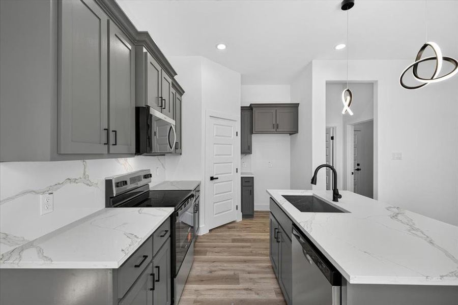 Modern kitchen featuring gray cabinetry with matte black hardware, white countertops, and a full-height white backsplash Modern kitchen featuring gray cabinetry with matte black hardware, white countertops, and a full-height white backsplash