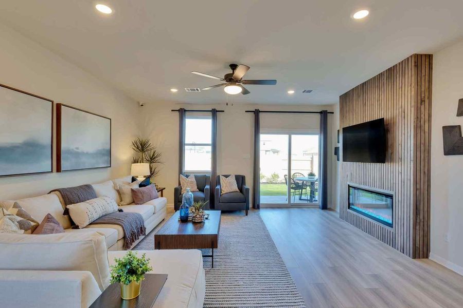 Natural light floods this inviting living space, highlighting its sleek flooring and cozy fireplace feature wall.