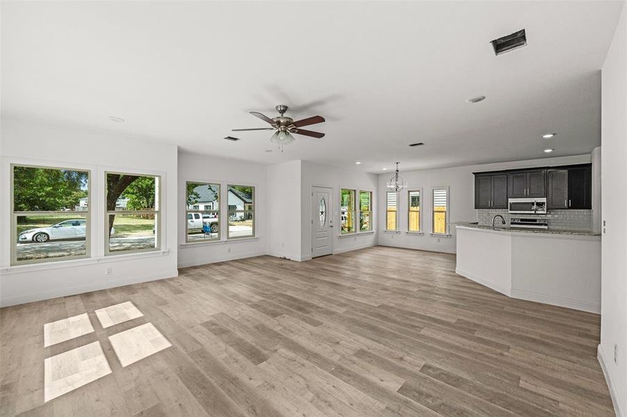 Unfurnished living room with sink, ceiling fan, and light wood-type flooring