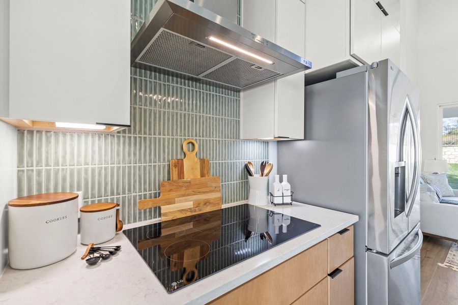 Kitchen with extractor fan, black electric stovetop, modern cabinets, and light stone counters