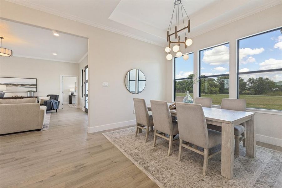 Dining area featuring large windows, a contemporary chandelier, crown molding, and wood-finish flooring
