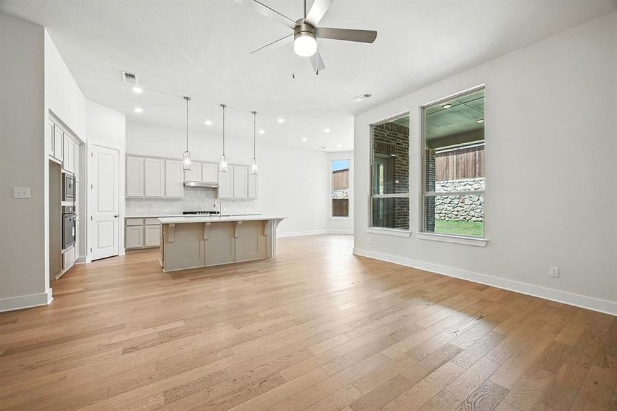 Kitchen with an island with sink, tasteful backsplash, open floor plan, pendant lighting, and light wood-style floors Kitchen with an island with sink, tasteful backsplash, open floor plan, pendant lighting, and light wood-style floors