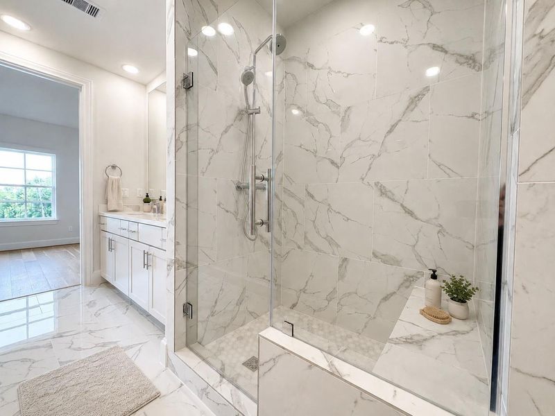 Primary bath with tall mirrors and large walk in shower with bench seat.