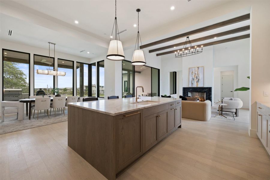 Kitchen with a fireplace, light wood-type flooring, open floor plan, and a sink Kitchen with a fireplace, light wood-type flooring, open floor plan, and a sink