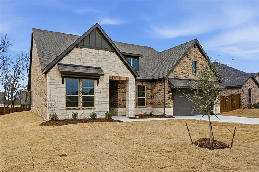 View of front of property with stone siding, driveway, a shingled roof, board and batten siding, and brick siding View of front of property with stone siding, driveway, a shingled roof, board and batten siding, and brick siding