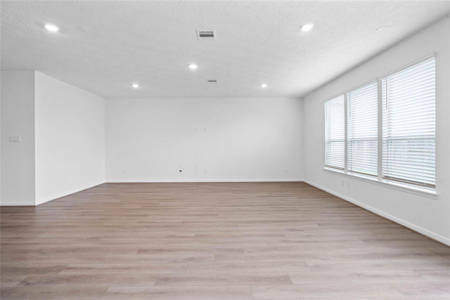 Gather the family and guests together in your lovely family room! Featuring high ceilings, recessed lighting, custom paint, vinyl plank flooring, and large windows with blinds.