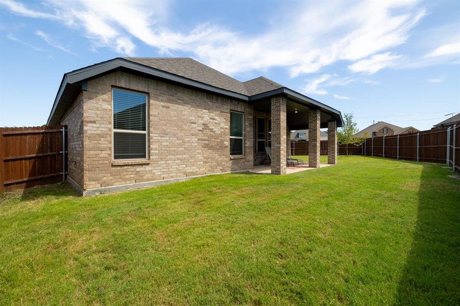 Rear view of property with a fenced backyard, a patio area, roof with shingles, and brick siding