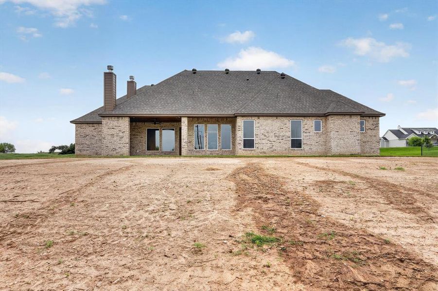 Brick exterior featuring multiple tall windows and a covered patio with an outdoor fan Brick exterior featuring multiple tall windows and a covered patio with an outdoor fan
