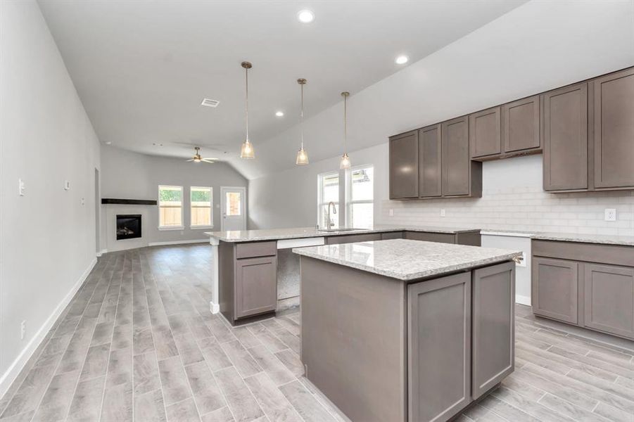 Experience the epitome of a dream kitchen in this generously spacious layout! Revel in features like a massive granite island, high ceilings, soft-close cabinets, granite countertops, stainless steel appliances, a sleek tile backsplash, and recessed lighting. The extended counter area provides additional functionality. With an open concept design, this kitchen seamlessly connects to the expansive family room, creating a perfect and inviting hub for gatherings.  Sample photo.