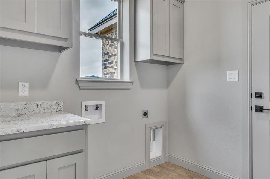 Washroom with cabinets, electric dryer hookup, light hardwood / wood-style flooring, and hookup for a washing machine