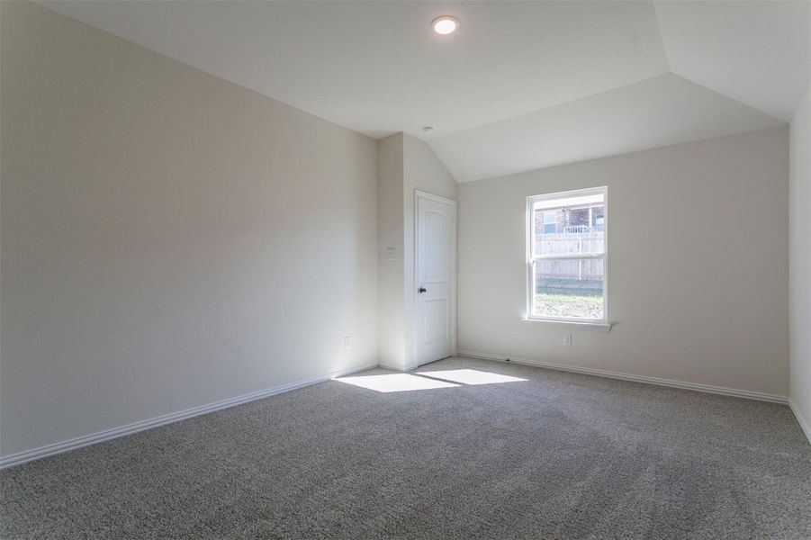 Carpeted spare room featuring lofted ceiling and baseboards Carpeted spare room featuring lofted ceiling and baseboards