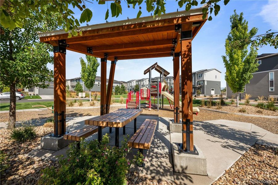 Shaded pergola seating area within the neighborhood park, offering picnic-style tables and easy access to the playground and walking paths.