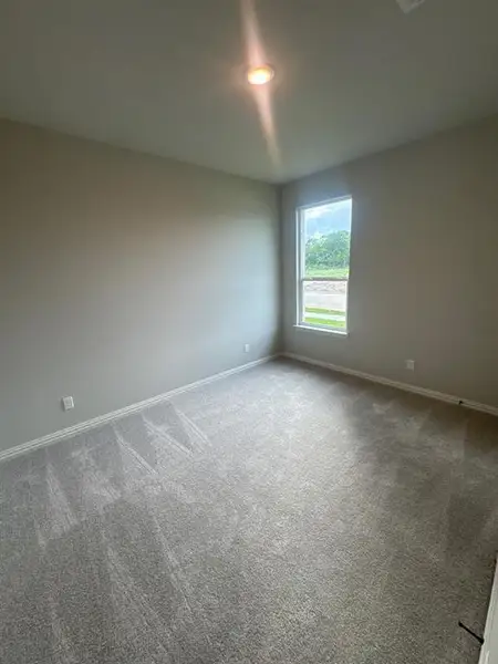Spacious room featuring neutral carpeting, light-toned wall paint, recessed lighting, and a window with white trim