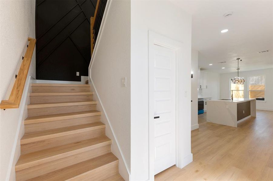 Stairs with wood finished floors and hanging lights