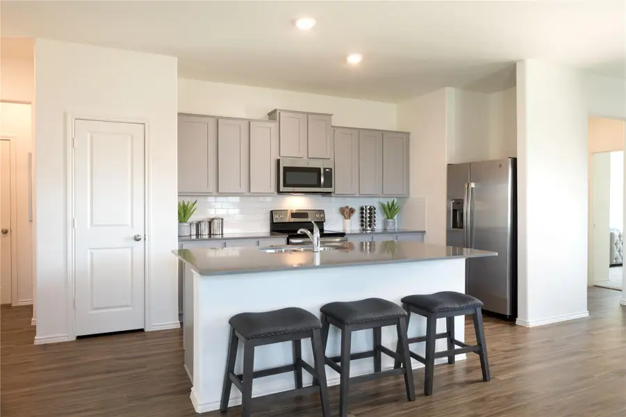 Kitchen with appliances with stainless steel finishes, a kitchen island with sink, tasteful backsplash, gray cabinets, and a kitchen breakfast bar Kitchen with appliances with stainless steel finishes, a kitchen island with sink, tasteful backsplash, gray cabinets, and a kitchen breakfast bar