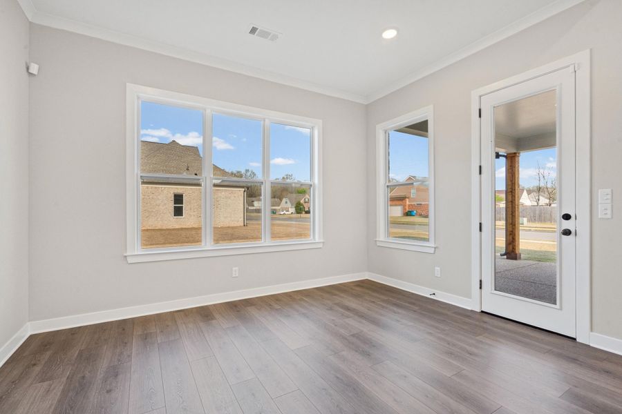 Spare room with ornamental molding, plenty of natural light, and dark wood-style flooring