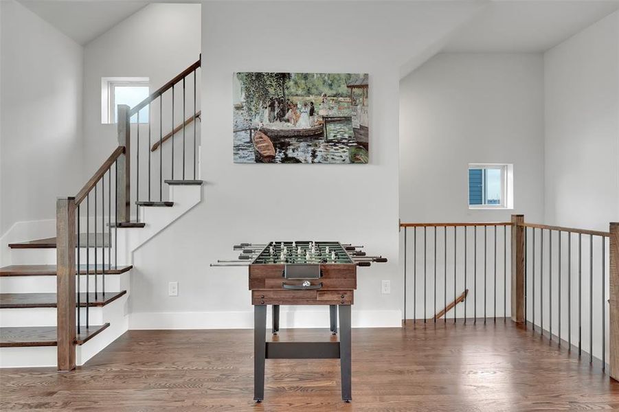 Staircase with plenty of natural light, wood finished floors, and a high ceiling