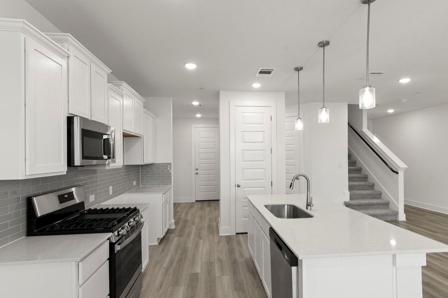 Kitchen featuring stainless steel appliances, backsplash, light stone countertops, white cabinetry, and dark wood-type flooring