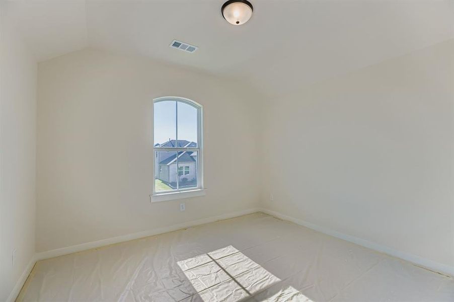 Carpeted empty room with lofted ceiling and baseboards