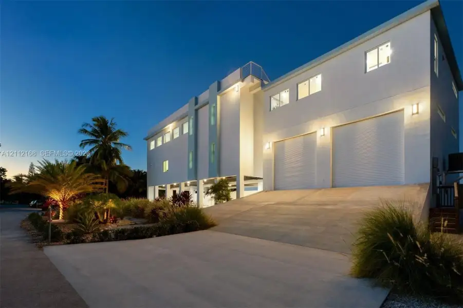 Contemporary multi-level exterior featuring a stucco facade, double-bay roll-up garage, concrete driveway, and elevated architectural detailing Contemporary multi-level exterior featuring a stucco facade, double-bay roll-up garage, concrete driveway, and elevated architectural detailing