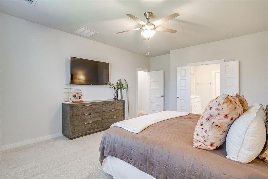 Bedroom with light colored carpet, ceiling fan, and connected bathroom Bedroom with light colored carpet, ceiling fan, and connected bathroom