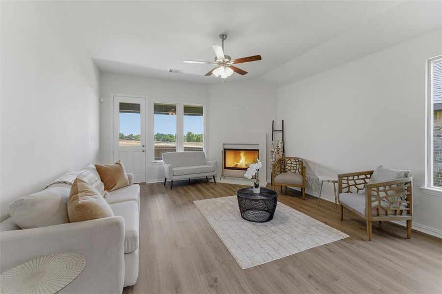 Spacious living area featuring wood-finish flooring, a corner fireplace, and a ceiling fan