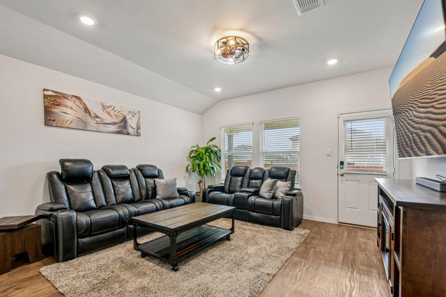 Living room featuring vaulted ceiling, light wood-style floors, and recessed lighting