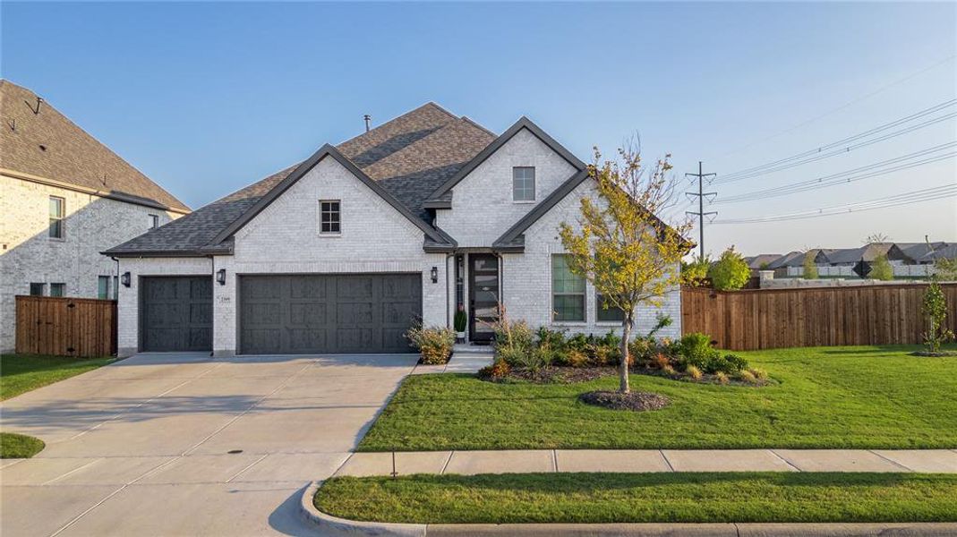French country inspired facade featuring brick siding, roof with shingles, driveway, and a garage French country inspired facade featuring brick siding, roof with shingles, driveway, and a garage