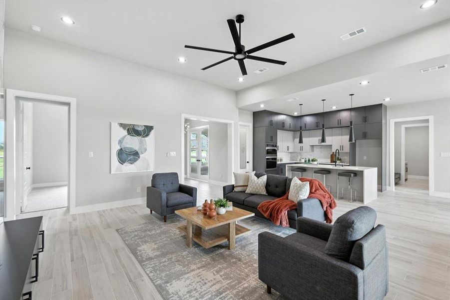 Living room with a ceiling fan, light wood finished floors, and recessed lighting Living room with a ceiling fan, light wood finished floors, and recessed lighting