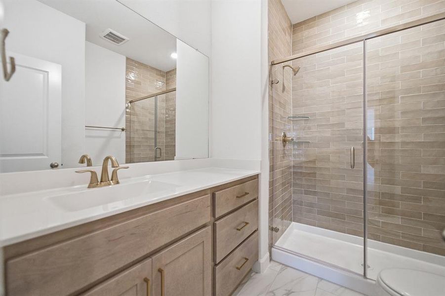 Spacious bathroom featuring a single vanity with a white countertop and gold-toned fixtures Spacious bathroom featuring a single vanity with a white countertop and gold-toned fixtures