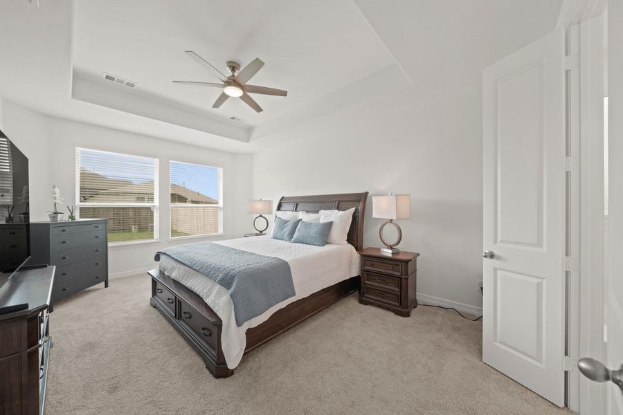 The generously sized primary bedroom enjoys natural light from windows overlooking the fenced backyard.