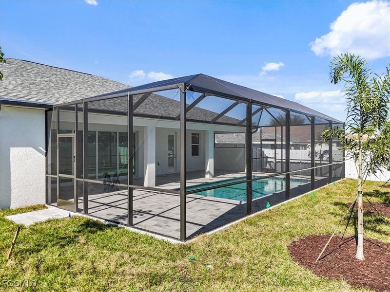 Rear view of house with a sunroom, stucco siding, a lanai, roof with shingles, and a patio